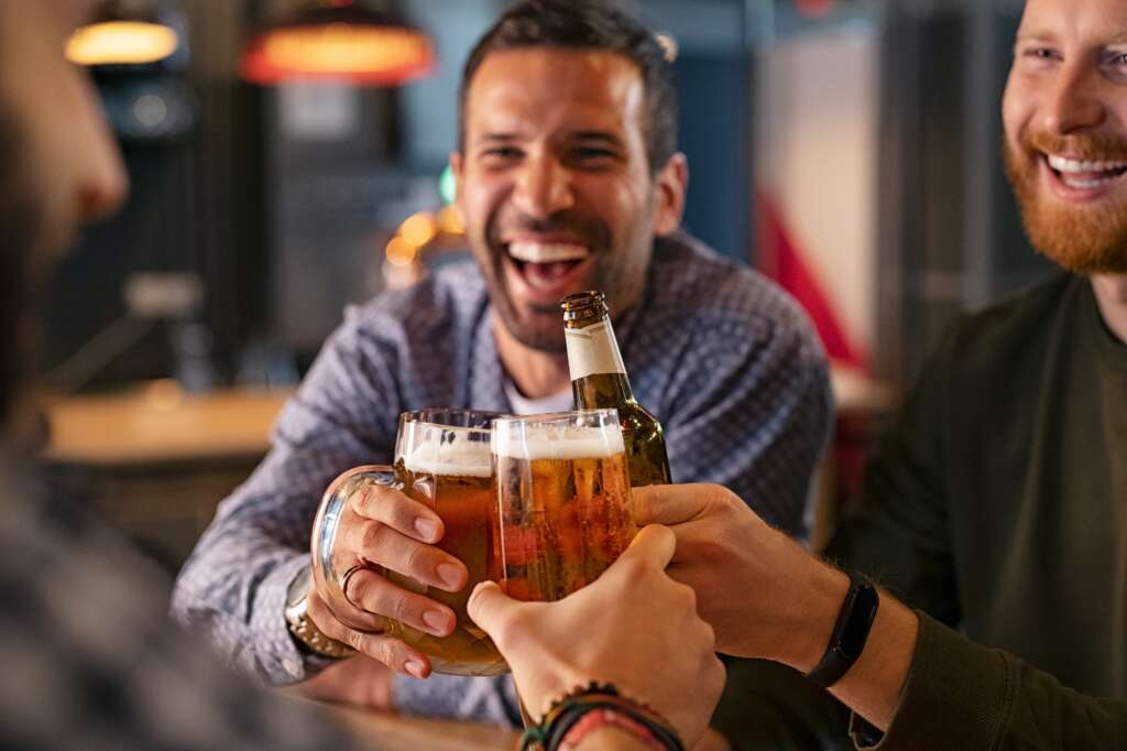 Friends toasting beer glass and bottle